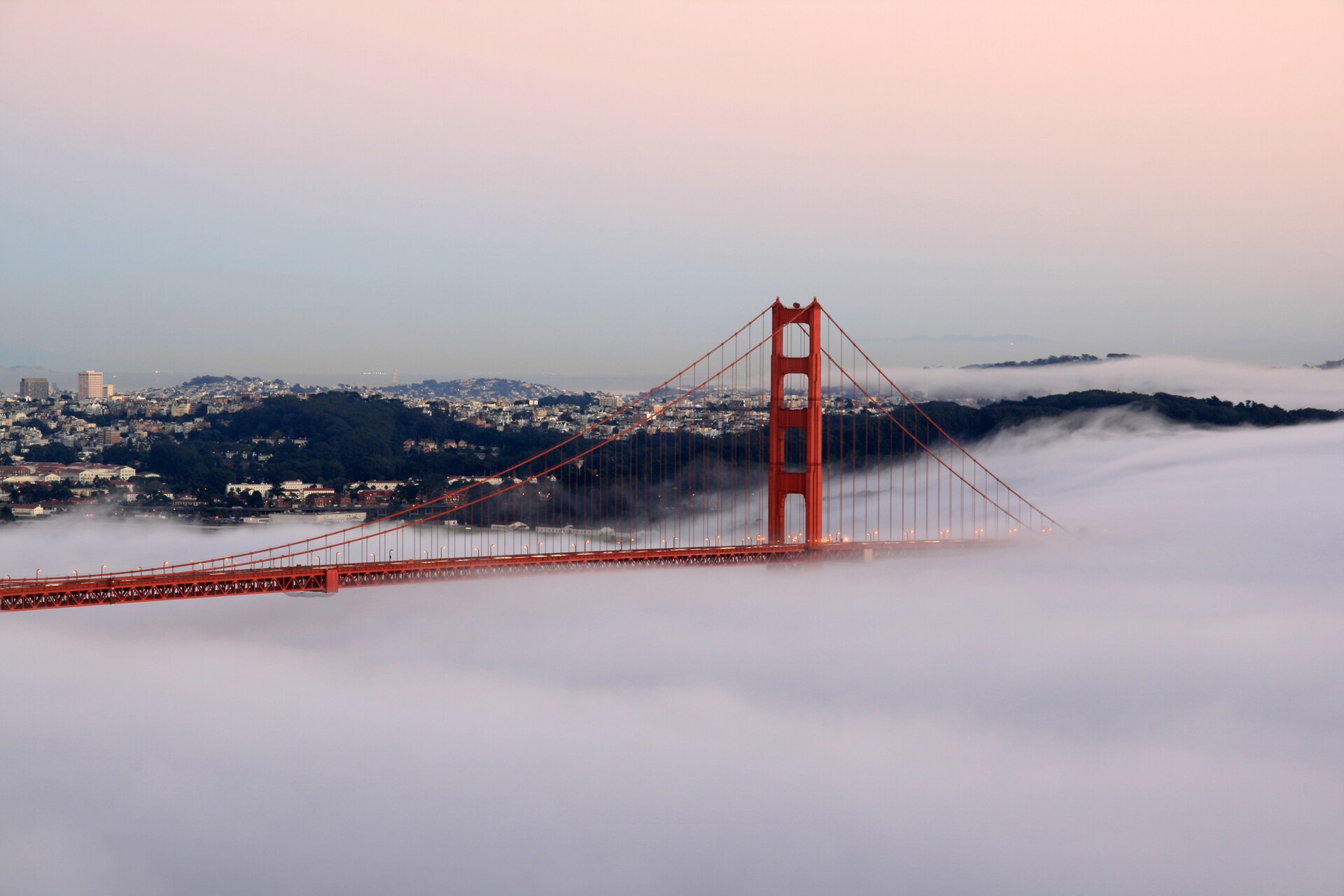 Golden Gate Bridge rising above coastal fog at sunset in San Francisco, California.